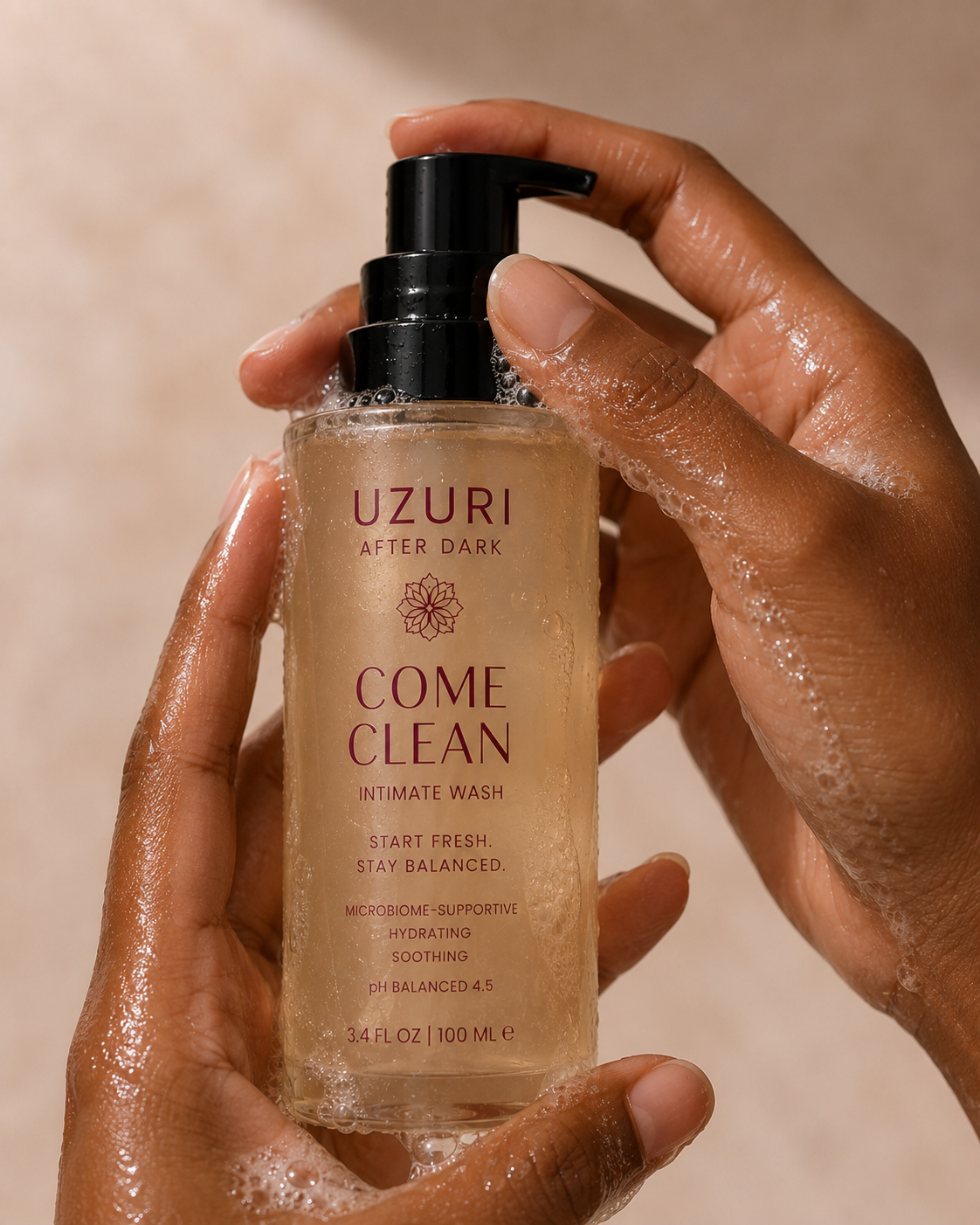 Person holding a bottle of Uzuri 'Come Clean' intimate wash with a beige background